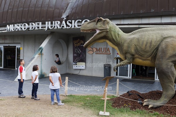 Tres niños miran con interés una reproducción de dinosaurio a la entrada del Museo del Jurásico de Asturias. Colunga. Asturias. España © Javier Prieto Gallego